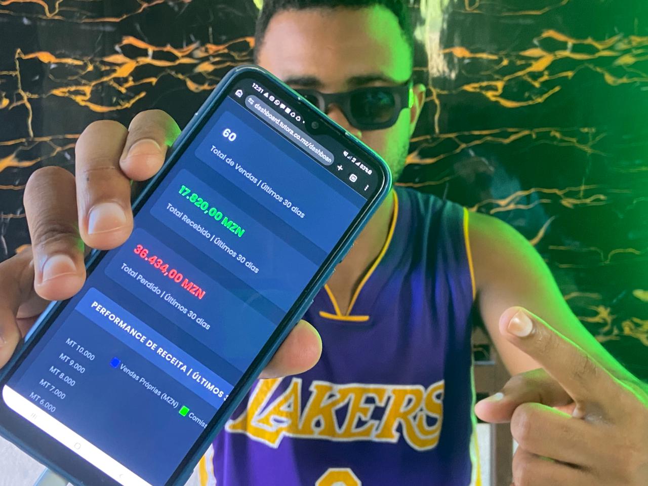 Participante a mostrar o painel de vendas no telemóvel